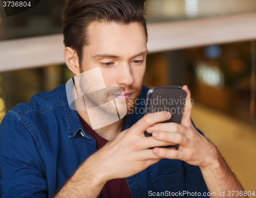 Image of man with smartphone reading message at restaurant