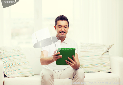 Image of smiling man working with tablet pc at home