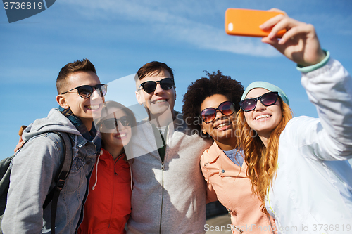 Image of smiling friends taking selfie with smartphone