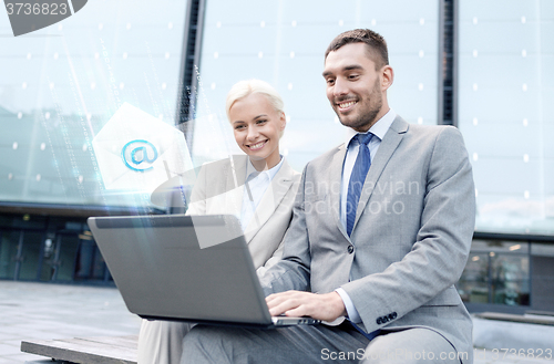 Image of smiling businesspeople with laptop sending e-mail