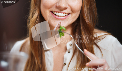 Image of happy young woman having dinner at restaurant
