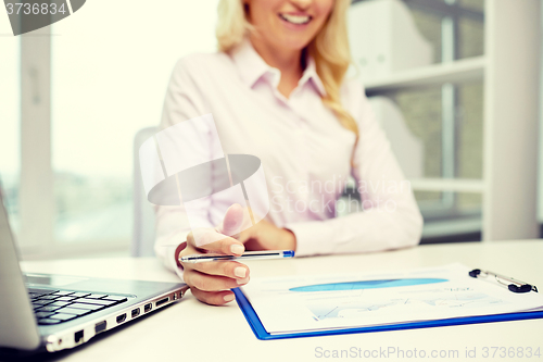 Image of smiling businesswoman reading papers in office