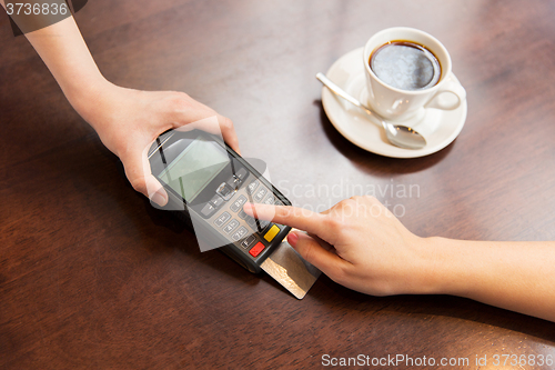 Image of close up of hands with credit card reader at cafe