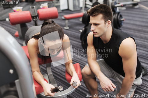 Image of young woman with trainer exercising on gym machine