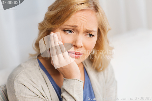 Image of unhappy woman suffering toothache at home