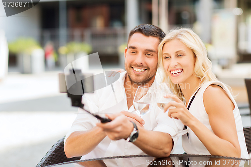 Image of happy couple taking selfie with smartphone at cafe