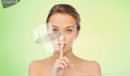 Image of beautiful young woman holding finger on lips