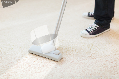 Image of close up of male hoovering carpet