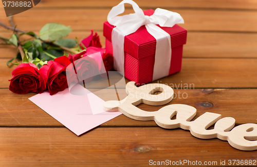 Image of close up of gift box, red roses and greeting card