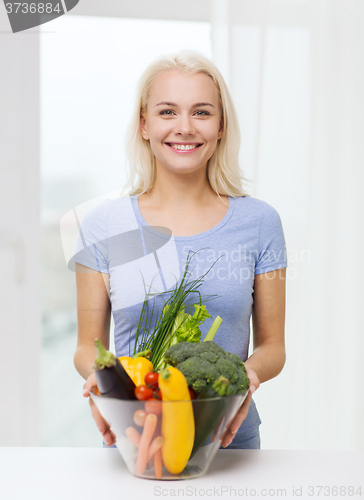 Image of smiling young woman with vegetables at home