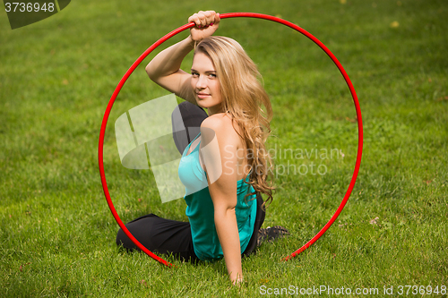 Image of Young female athlete with hula hoop in the park