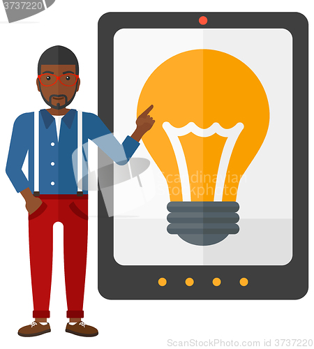 Image of Man pointing at tablet computer with light bulb on screen.