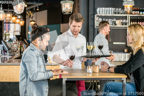 Image of Waiter Serving Wine To Customers In Bar