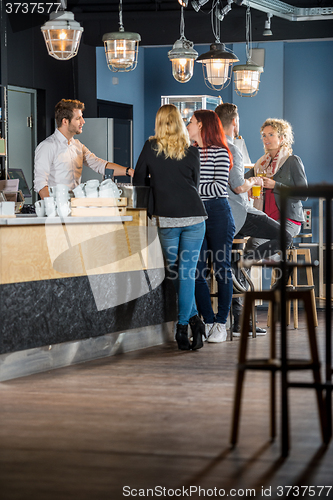 Image of Customers With Bartender Standing At Counter