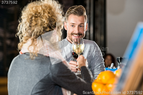 Image of Man Toasting Wine With Friend In Bar