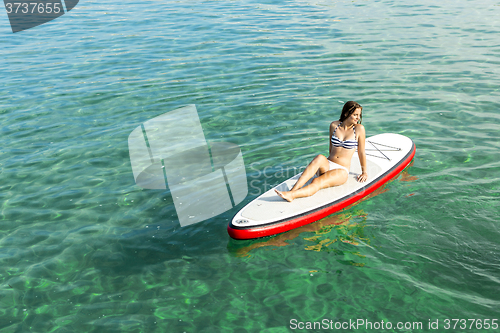 Image of Woman relaxing over a paddle surfboard