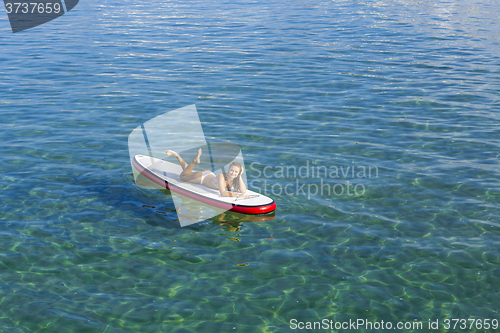 Image of Woman relaxing over a paddle surfboard