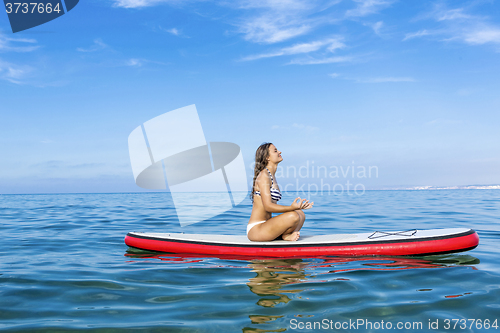 Image of Woman relaxing over a paddle surfboard