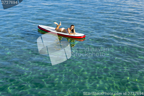 Image of Woman relaxing over a paddle surfboard