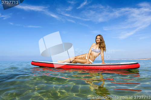 Image of Woman sitting over a paddle surfboard