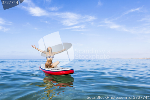 Image of Woman relaxing over a paddle surfboard