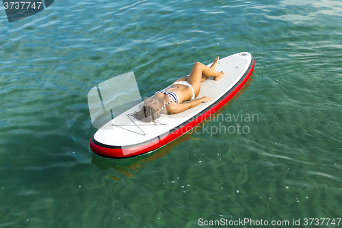 Image of Woman relaxing over a paddle surfboard