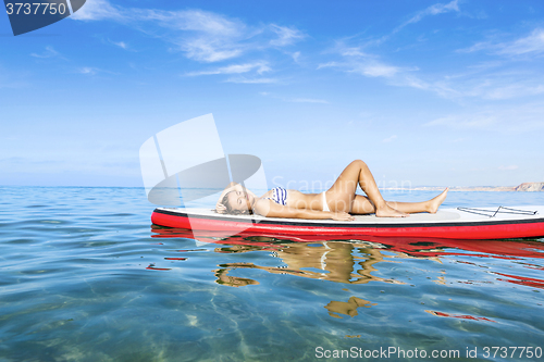 Image of Woman relaxing over a paddle surfboard
