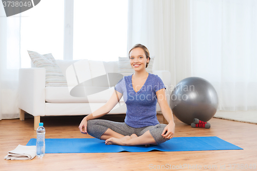Image of woman making yoga in lotus pose on mat
