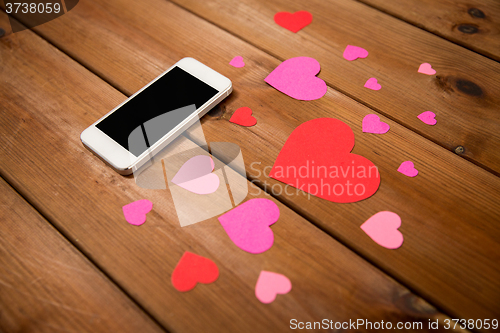 Image of close up of smartphone and hearts on wood