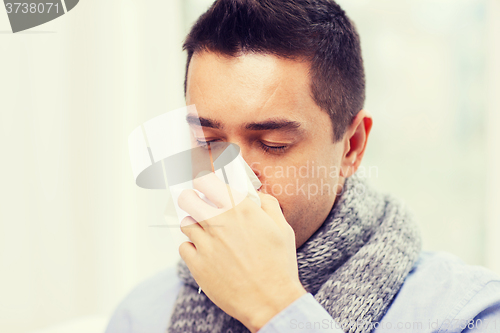 Image of close up of ill man with flu blowing nose at home