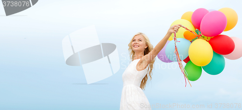 Image of smiling woman with colorful balloons outside