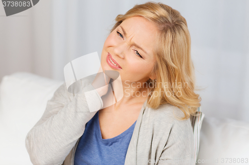 Image of unhappy woman suffering from neck pain at home