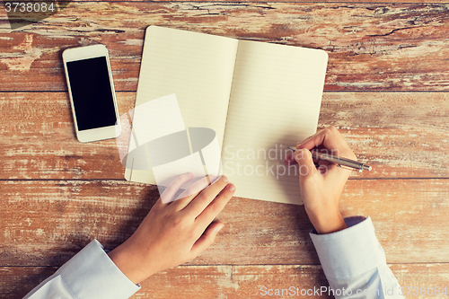 Image of close up of hands with notebook and smartphone