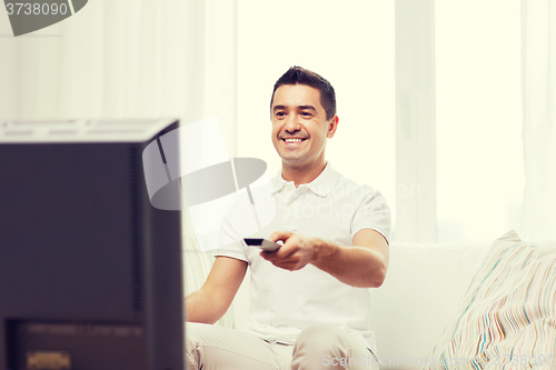 Image of smiling man with remote control watching tv