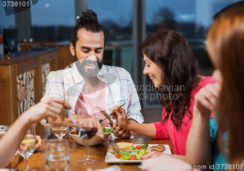 Image of friends eating and tasting food at restaurant