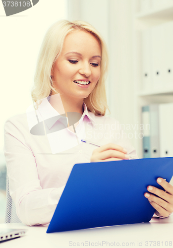 Image of smiling businesswoman with clipboard in office