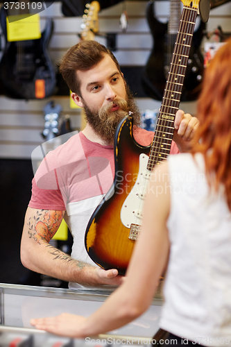 Image of assistant showing customer guitar at music store