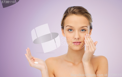 Image of young woman applying cream to her face