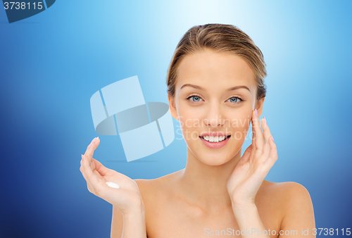 Image of happy young woman applying cream to her face