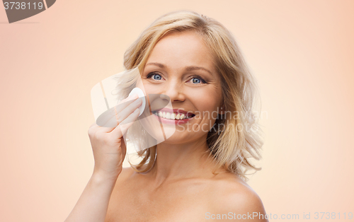 Image of happy woman cleaning face with cotton pad