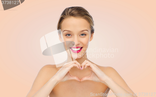Image of smiling young woman showing heart shape hand sign