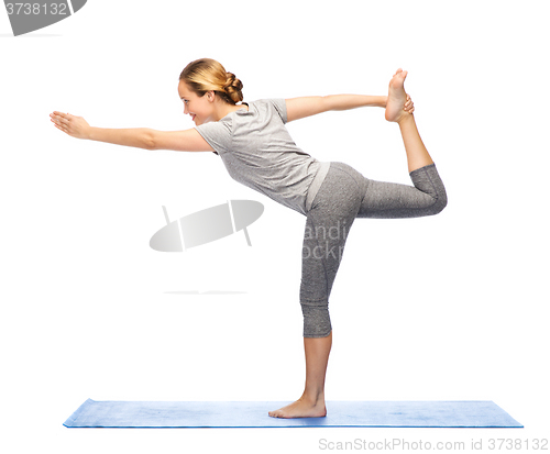 Image of woman making yoga in lord of the dance pose on mat