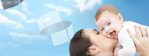 Image of happy mother kissing her baby over blue sky