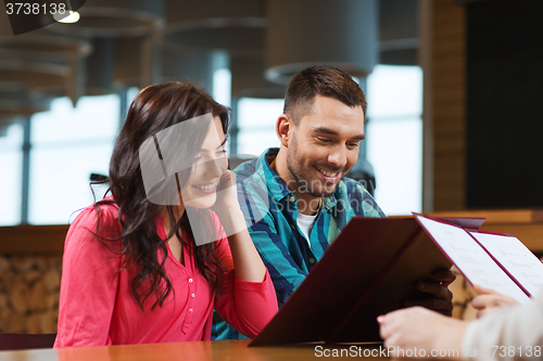 Image of smiling couple with menus at restaurant