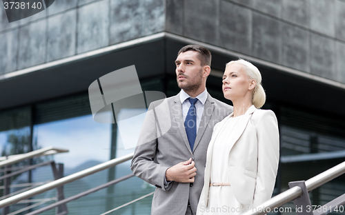 Image of serious businessmen standing over office building