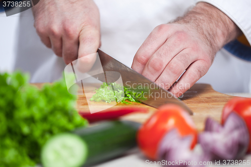 Image of Chef cutting a green lettuce his kitchen