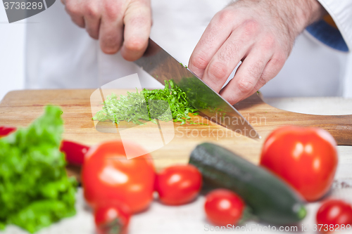 Image of Chef cutting a green lettuce his kitchen