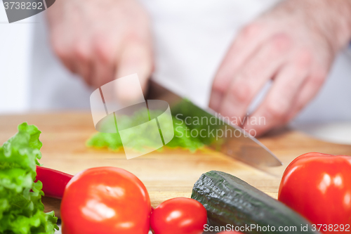 Image of Chef cutting a green lettuce his kitchen