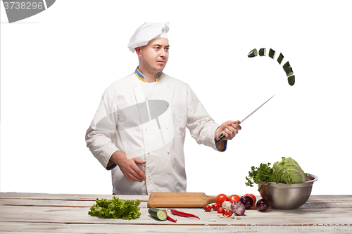 Image of Chef cutting a green cucumber in his kitchen