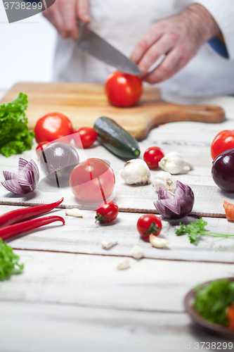 Image of Chef cutting a red tomato his kitchen